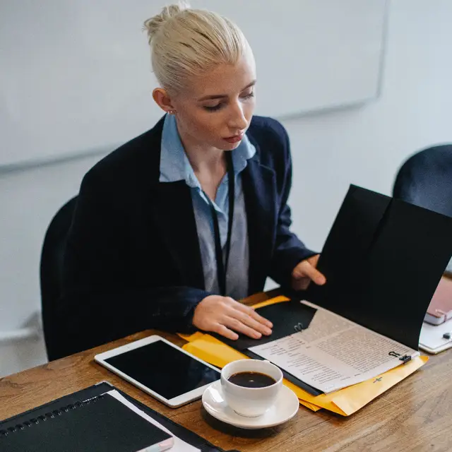 Eine Person in einem B&uuml;ro, die eine Akte aufschl&auml;gt.